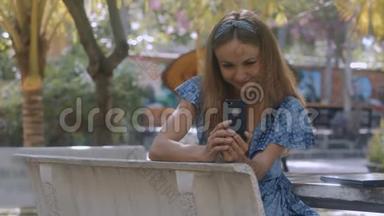 漂亮女孩在公园的石凳上看<strong>iphone短信</strong>